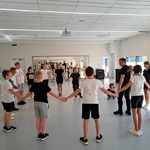 Uczniowie podczas warsztatów tanecznych - trzymają się za ręce i tworzą kółko.jpg
