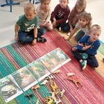 Dzieci siedzące na dywanie oglądają zdjęcia zwierząt.jpg