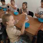 Dzieci siedzące przy stole i robiące slime.jpg