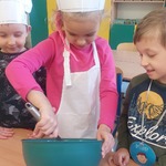 Dzieci w czapkach kucharskich mieszają produkty potrzebne do wypieku chleba.jpg