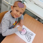 Chłopiec w czapeczce z przyklejonym narysowanym burakiem - koloruje